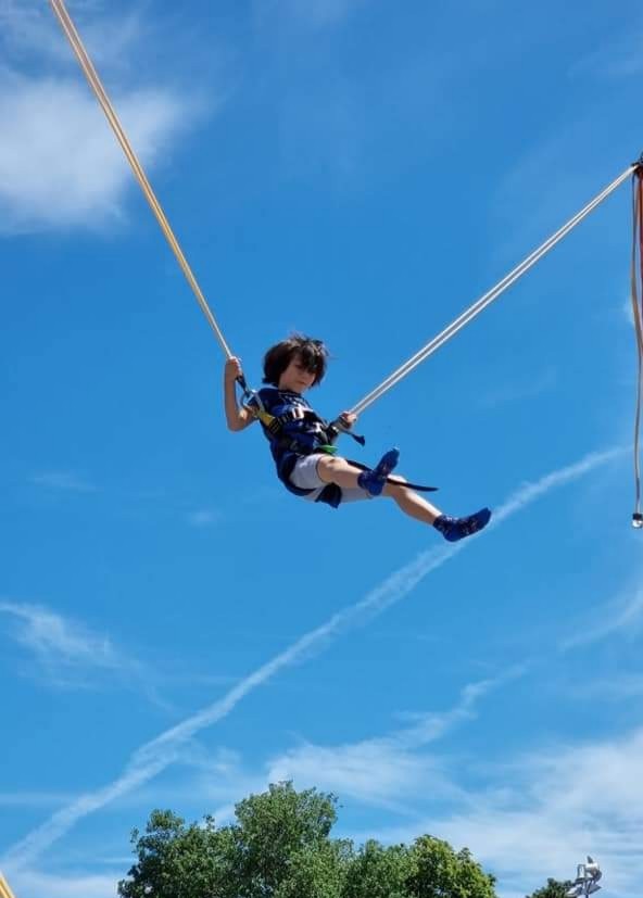 Kind beim Bungee-Trampolin vor blauem Himmel